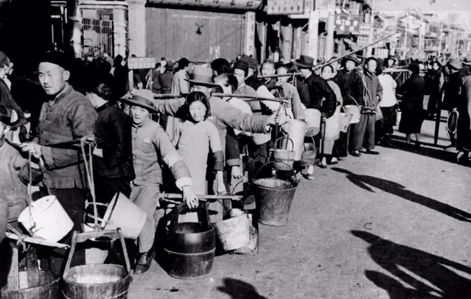 Shorn Of Their Homes - Chinese refugees are grateful for the food - of a necessity doled out sparingly - which they receive at the relief centres in Shanghai Now, in some parts, even water is a precious possession. This is a scene outside the French concession, Rue des Deuz Republiques in Shanghai where water is distributed from the French mains as there is no water in the Jacquinot Refugee Zone. January 25, 1938. (Photo by Topical Press).