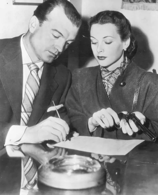 Hedy And Mate Seek Gun Permit -- Actress Hedy Lamarr holds a revolver as her husband, John Loder, signs an application for a gun permit at police head quarters today. Their home was burglarized the other night of $18,400 in furs and Jewelry.Film Stars Hedy Lamarr and husband John Loder recently signed an, application for a revolver permit after their home had been burgled. Hedy Lamarr holding the revolver. Burglars took furs, jewelry, and 18,400 dollars. April 19, 1946. (Photo by AP Wirephoto).