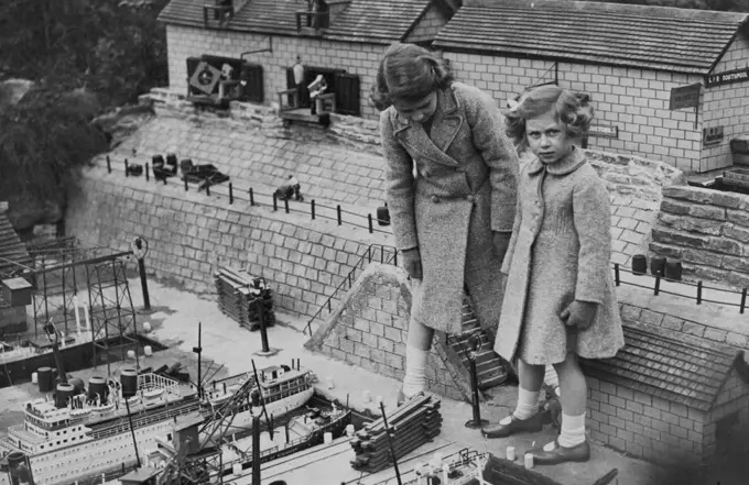 Little Princess Visit Model Village - Princess Elizabeth and Princess Margaret Rose interested in the model docks and shipping.Princess Elizabeth and Princess Margaret Rose today paid a visit to the model village of "Bekonscot," at Beaconsfield, Buckinghamshire. April 15, 1936. (Photo by Topical Press).