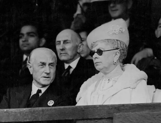 Queen Mary At Wimbledon's Opening Day -- Queen Mary, wearing dark glass watching the play from the royal box on the centre court at Wimbled this afternoon, June 26. With her Majesty is Sir Samuel Hoare, The British Home Secretary, who is also President of the British Lawn Tennis Association. The 1939 Wimbledon tournament started today June 26, with a long programme of men's singles matches as the opening attractions of all the courts. The weather was unkind to the famous tournament right at the start, for low clouds made the conditions gloomy in the extreme and rain seemed to threaten at any moment. These conditions, however, did not Deter Queen Mary - A Real tennis enthusiast from attending, her Majesty arriving in the royal box on the centre court quite early in the afternoon, and watching a number of matches. July 01, 1939. (Photo by Associated Press Photo).