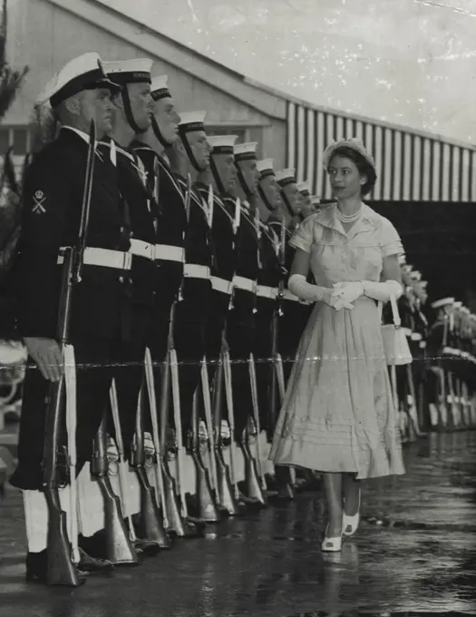 Attention - The Queen has a satisfied smile as she inspects the naval guard of honor immediately after arrival. True to navy tradition the guard stands strictly to attention, and although the Queen smiles not a muscle moves on the faces of the guard. December 23, 1953.