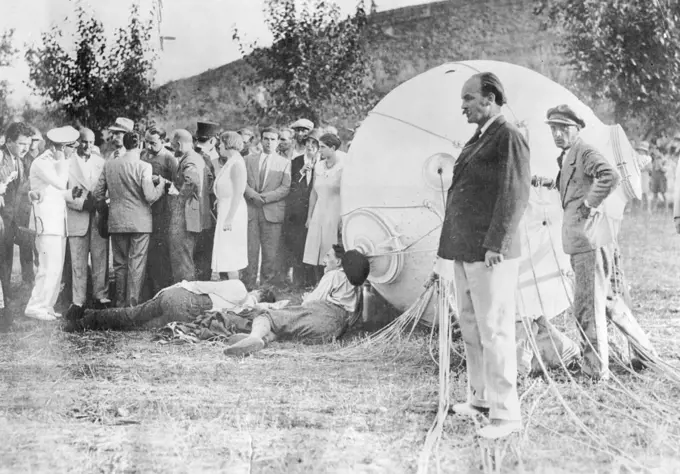Professor Piccard's Great Adventure In The Stratosphere -- Prof. Piccard and his assistant, M. Cosyns, lying on the ground exhausted just after landing. The change from the intense cold encountered during the journey to the summer heat an landing temporarily prostrated the intrepid scientists.When he and his companion Professor Cosyns landed in Northern Italy they collapsed in the heat after the sub-zero stratosphere temperatures. September 26, 1932.