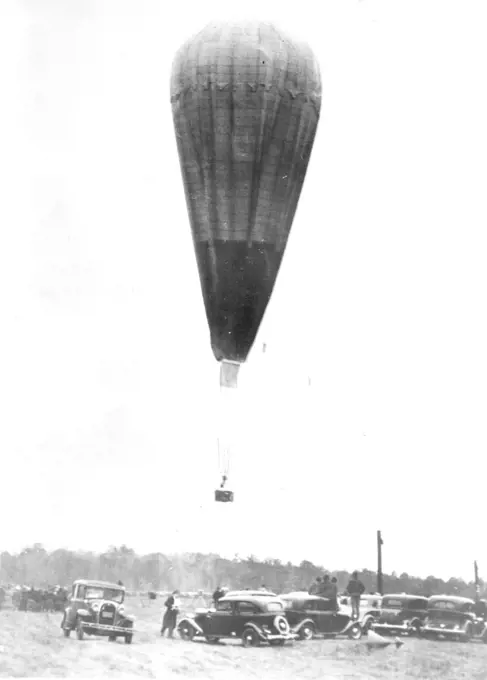 Aloft On Stratosphere Flight -- The wind had died to absolute calm as the balloon of Prof. and Mrs. Jean Piccard was cast off on its flight into the upper air Oct 23. The picture shows the big bag, which had a capacity of 600,000 cubic feet of hydrogen gas, as it left the ground at the ford Airport, near Detroit. The balloonists landed several hours later near Cadiz Ohio, unhurt. October 23, 1934. (Photo by Associated Press Photo).