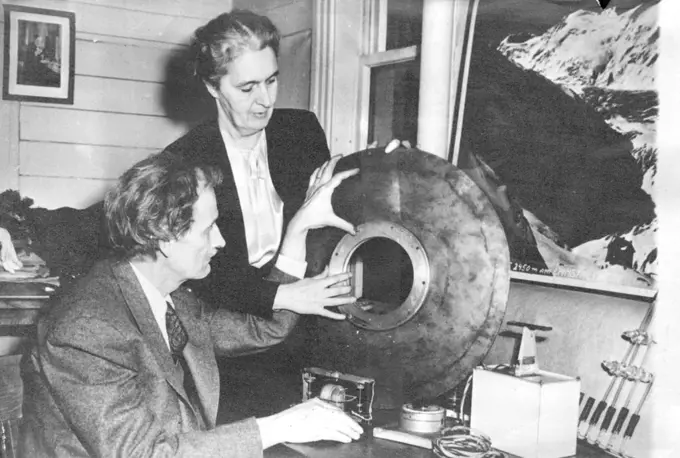Piccard Prepares For New Stratosphere Venture -- Dr. Jean Piccard (seated), the famous stratosphere flier, and his wife examine the new window he has perfected for a stratosphere gondola, in which the couple hope to make another stratosphere flight at Minneapolis. The picture was made at Minneapolis on Jan 4. May 11, 1952. (Photo by Associated Press Photo).