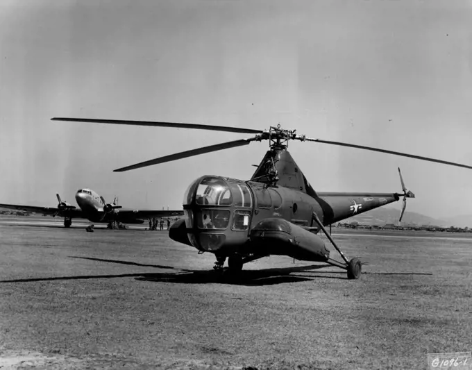 Static--And Active -- A tiny H-5 helicopter of the 3rd Air rescue Squadron sits silently at the ready, while a Far East Air forces C-47 Skytrain of the 315th Air Division (Combat Cargo) is loaded with troops bound for Japan for a well earned rest and recuperation leave. May 8, 1951. (Photo by U.S. Air Force Photo).
