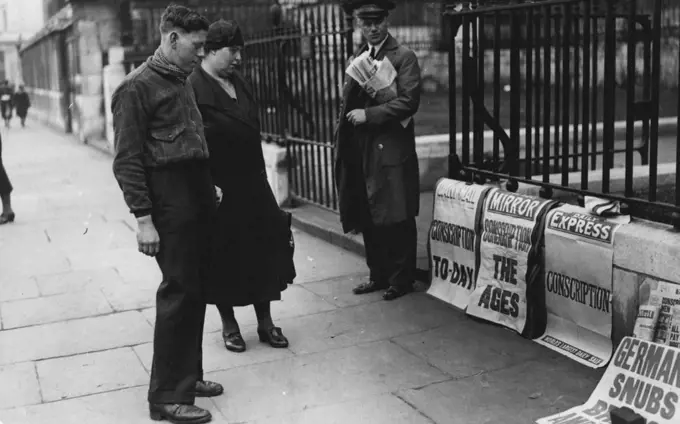 What Does *****Youth of military age studies the news paper posters announcing. Conscription, in London today (Wed). May 22, 1939. (Photo by London News Agency Photos Ltd.).