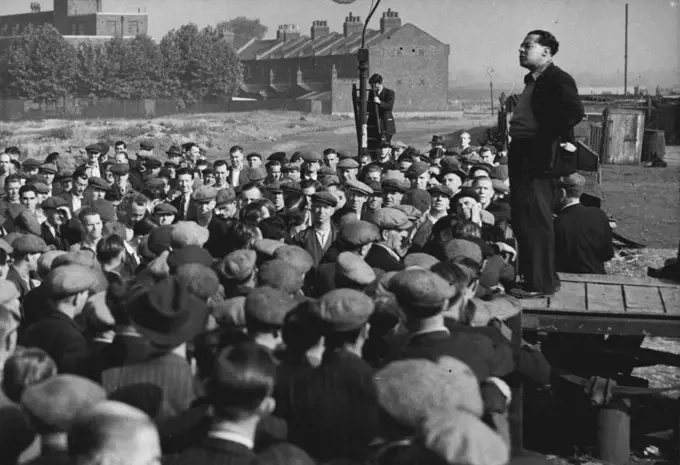 Dockers Hear 'Leader' On First Day of Emergency -- Crowd of London dockers listen to a speech by Albert Timothy, member of the unofficial 'lock out committee, at Royal.Victoria Dock to-day (Tuesday), first day of the State of Emergency regulations in the Port of London. More than 10,000 men are idle at the docks, and 112 ships are held up, owing to the refusal of the men to work the Canadian ships Beaverbrae and Argomont, which have been involved in a Canadian seamen strike. July 12, 1949. (Photo by Reuterphoto).