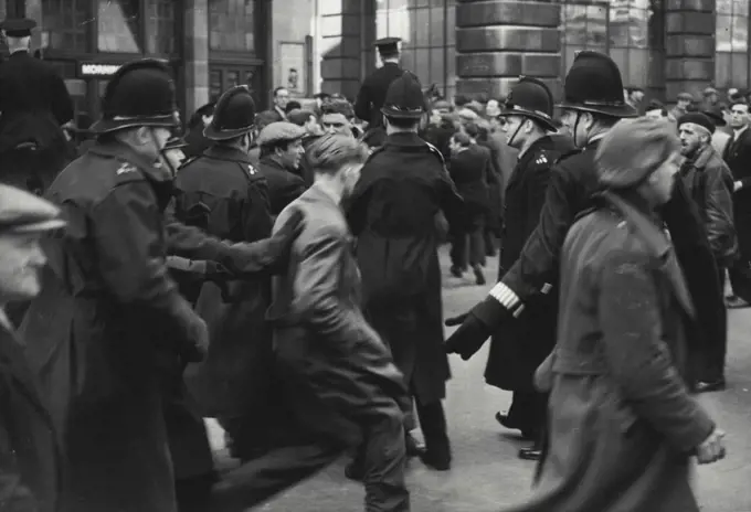 Police In Action As Dockers' Trail Ends -- A policeman uses his hands to urge a man away from the scene as foot and mounted police cleared dockers who massed near the old Bailey, London, to-day (Tuesday) when the trail of seven dockers - alleged to incite dockers to strike illegally - neared its end.Amid shouting, jeering and some scuffling, men who had gathered near the Old Bailey were driven by the police into side streets and roads away from the building. April 17, 1951. (Photo by Reuterphoto).