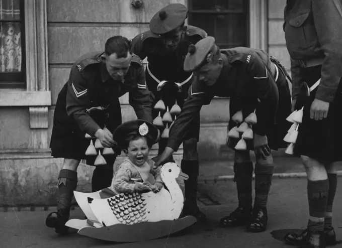 Baby Rides In Duck -- Born in married quarters at London's Wellington Barracks, eighteen-month-old Geoffrey Aylen is an Army man through and though. His daddy, Guards R.Q.M.S. Fred Aylen, would have been in yesterday's VE-Day anniversary march through London if he hadn't had to go to Malaya. Naturally, Geoffrey wanted to take his father's place in the march. And it took three stalwart Argyll and Sutherland Highlanders to persuade the youngster that his duck was a bit too slow. Now, if it had been a DUKW. May 06, 1949. (Photo by Daily Mirror).