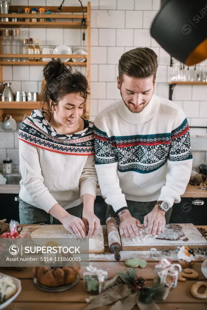 Friends in Christmas sweater make dough in the kitchen.