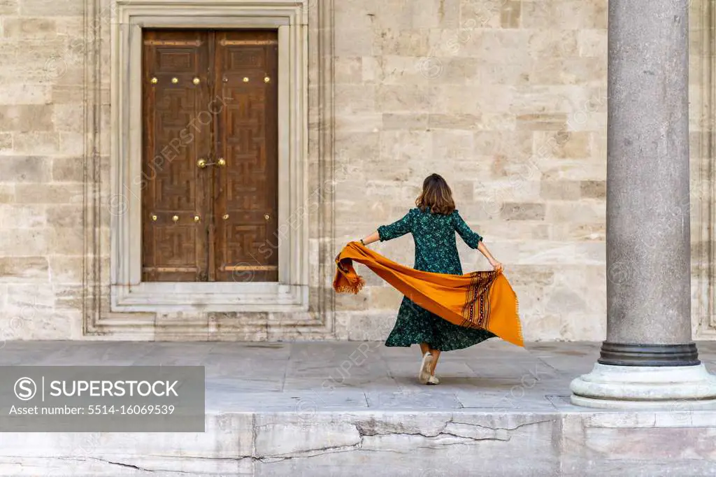 Woman in green dress and orange scarf exploring Istanbul on vacation