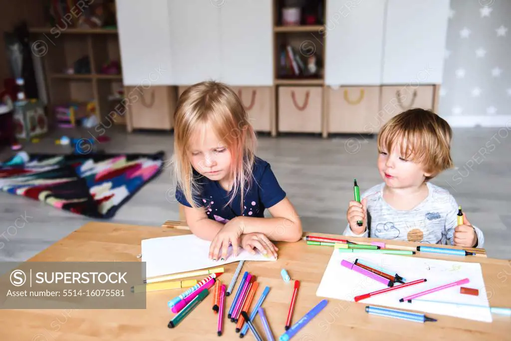 Little boy with sister drawing with felt-tip pens