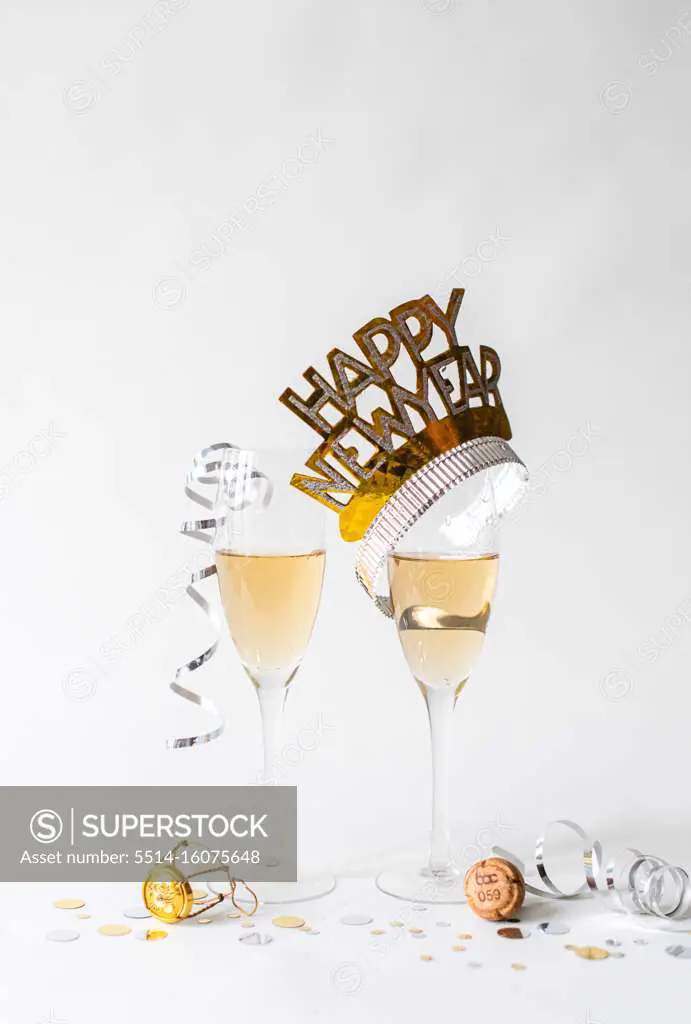 Glasses of champagne and Happy New Year hat on white background.