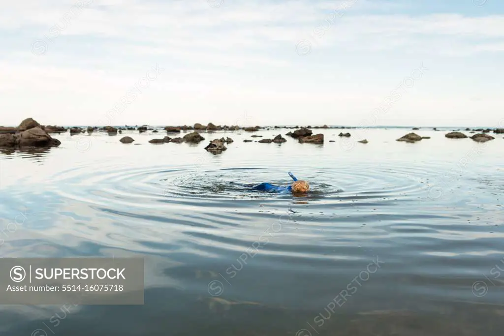 Young curly haired child snorkeling in New Zealand