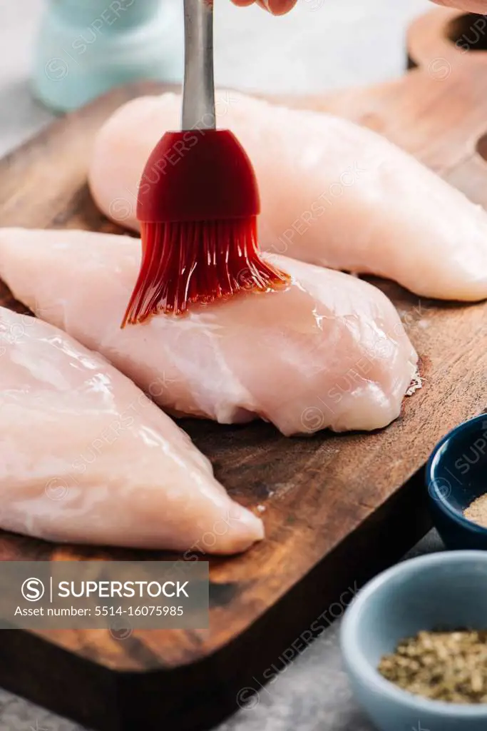 Brushing oil onto raw chicken breasts