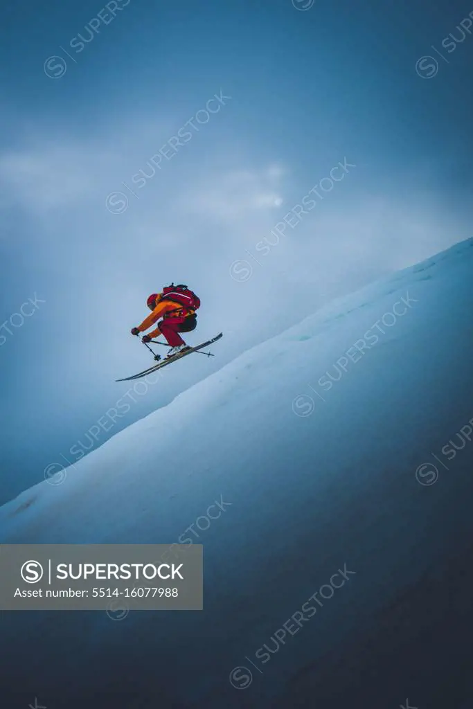 Skier going off ski jump with sky behind him