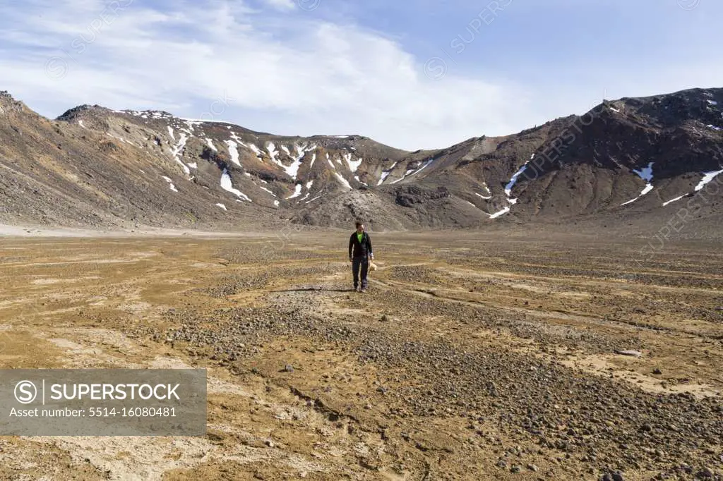 One man with a hat, standing in middle of desertic landscape