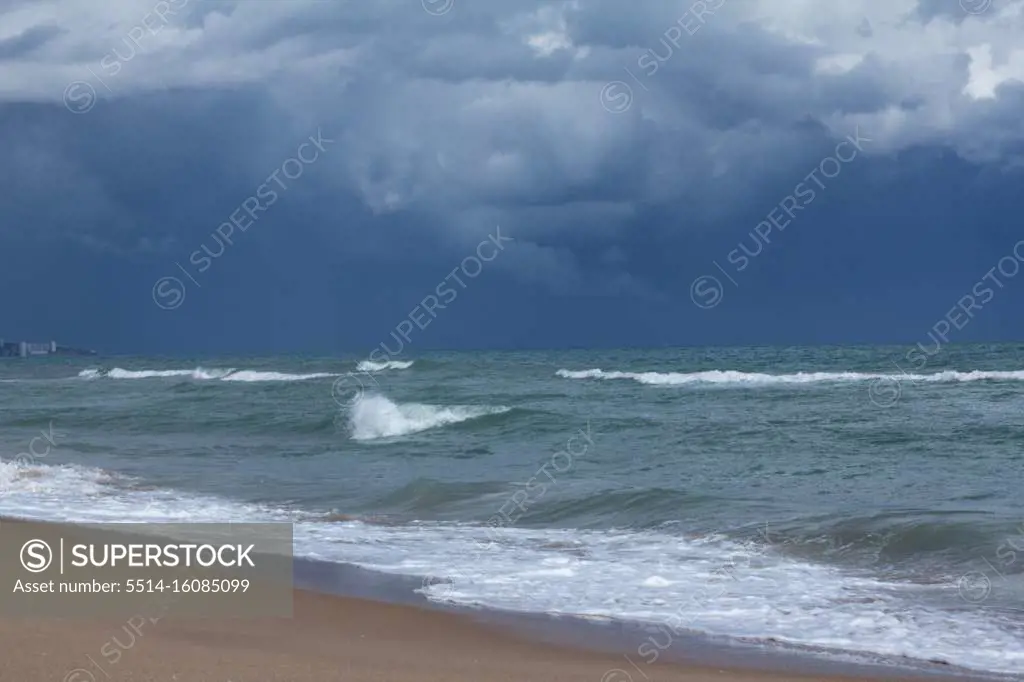 Landscape blue storm clouds over sandy beach with dark blue water