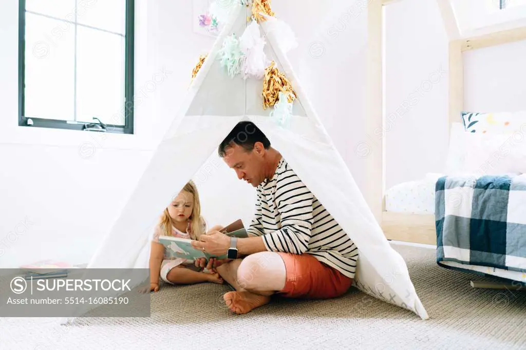 Closeup portrait of a dad and child reading together in a child's room