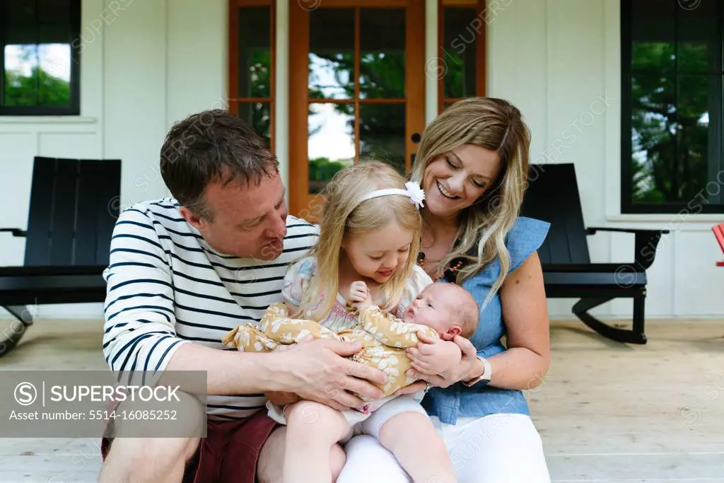 A new family sitting together on a modern farmhouse porch