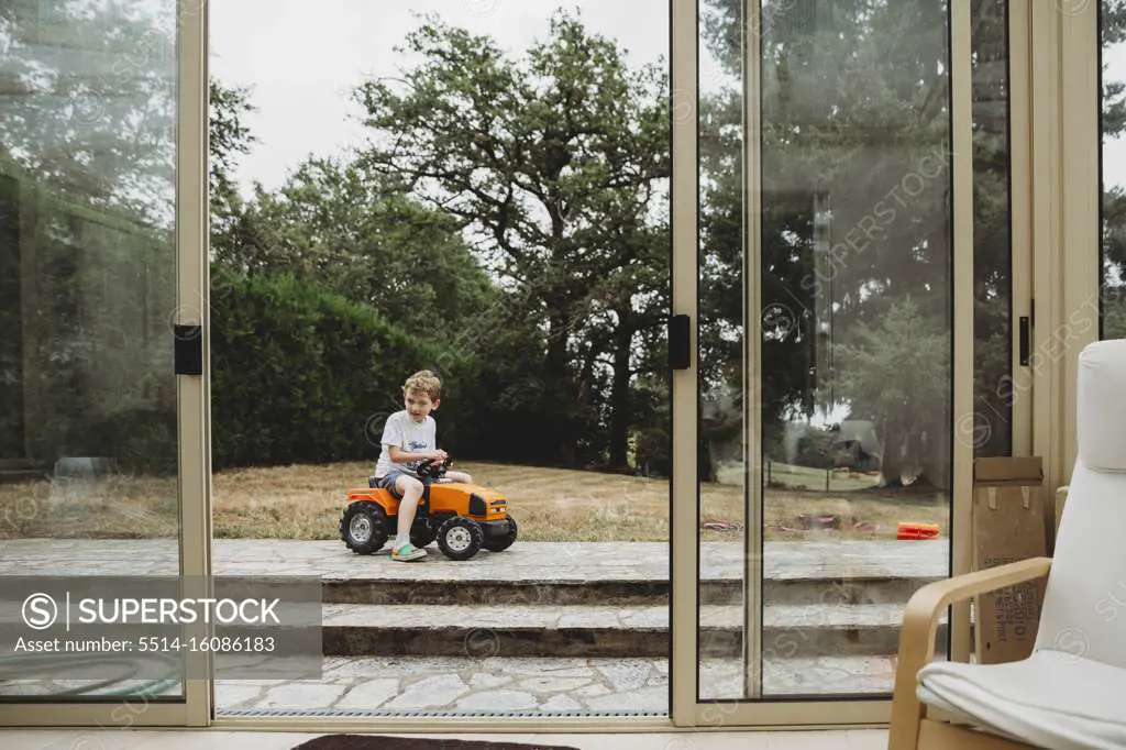 View through doors of boy on toy tractor