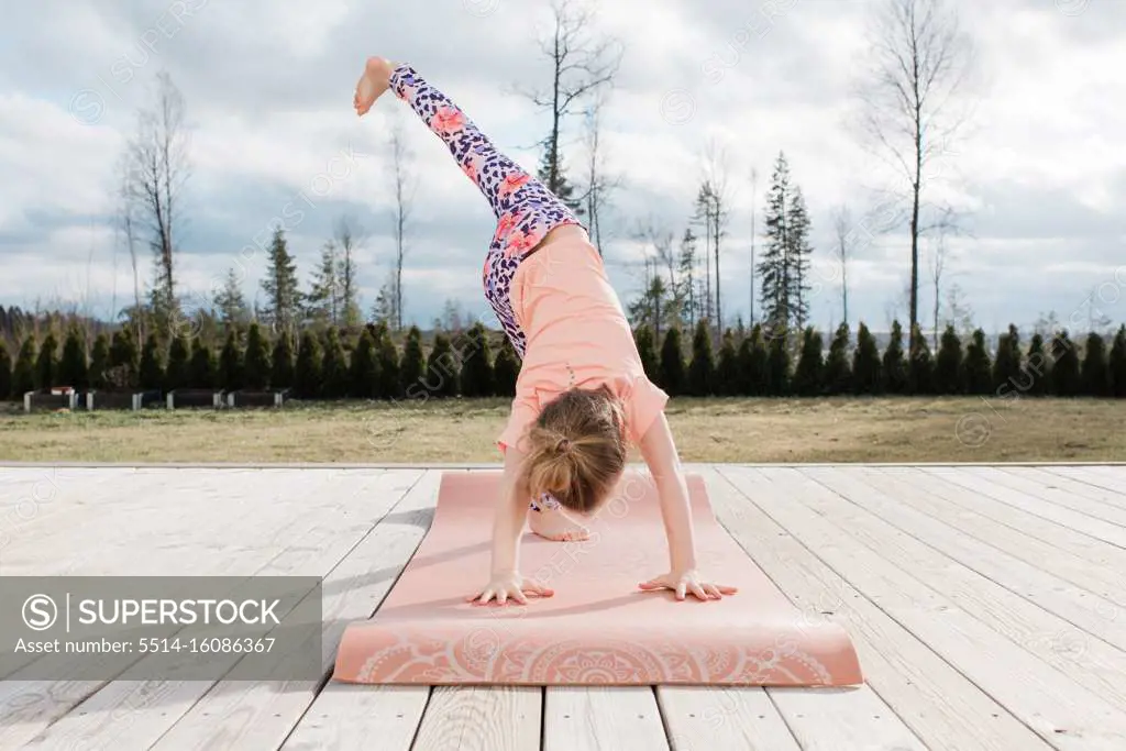 young girl stretching doing yoga in her back yard at home