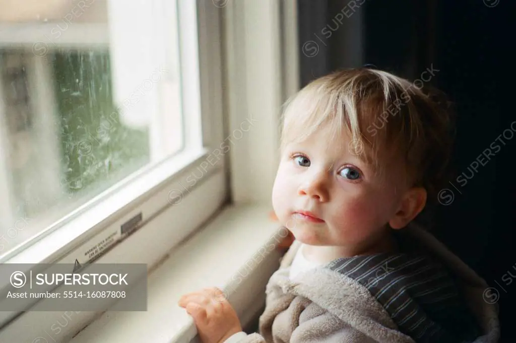 Film photo of a little girl standing by a window.