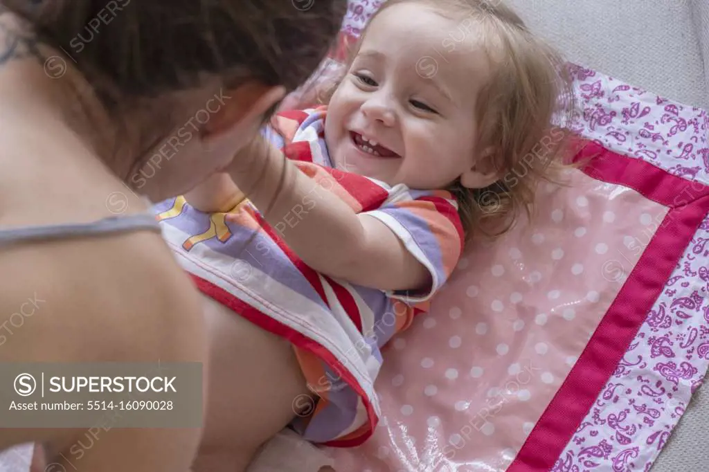 Mother changing diapers for her cute baby girl.