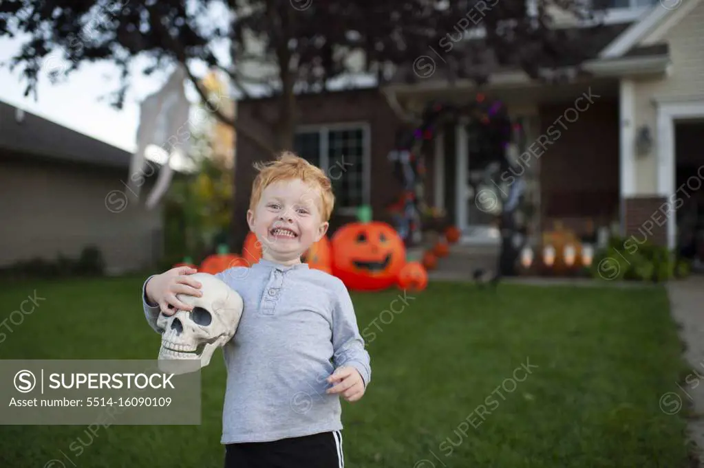 Toddler boy excited about holding skull in front of halloween decor