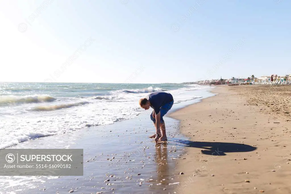 blond guy tourist in jeans enjoying the beach and the sea