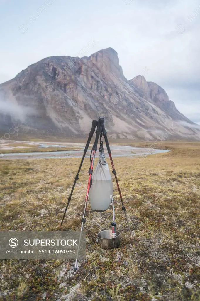 Gravity fed water filter held by tripod made with trekking poles.