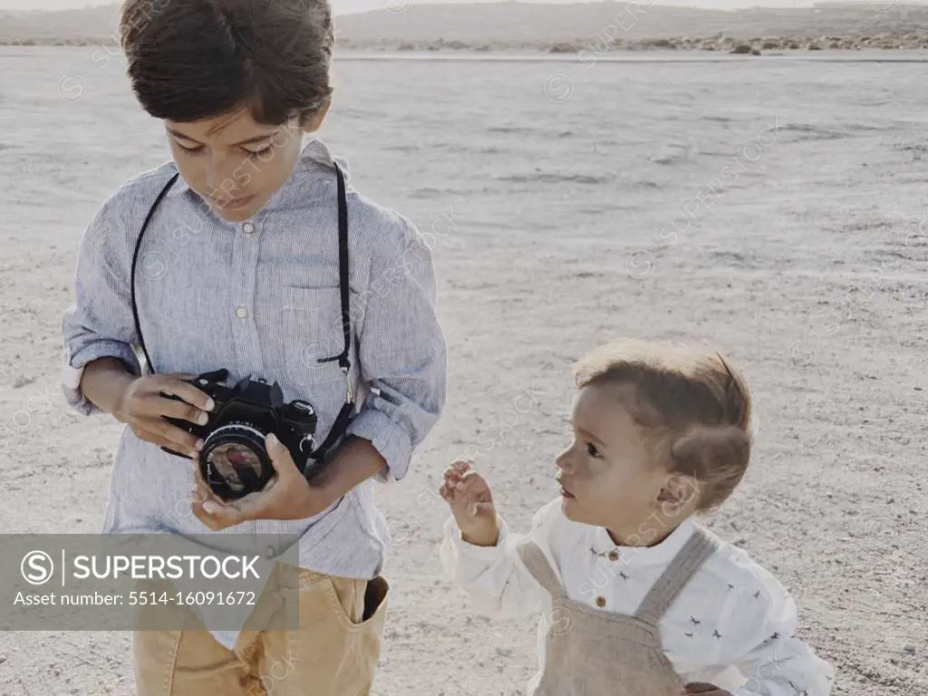 A kid holds a camera and a younger kid stands next to  me