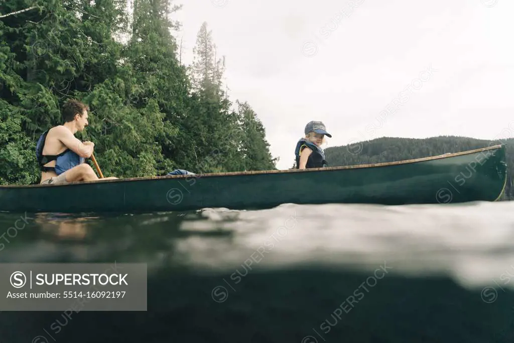 A young girl rides in a canoe with her dad on Lost Lake in Oregon.