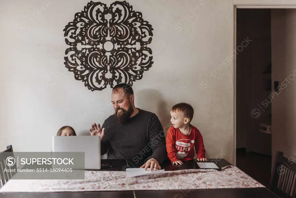 Young family video chatting and waving to family during isolation