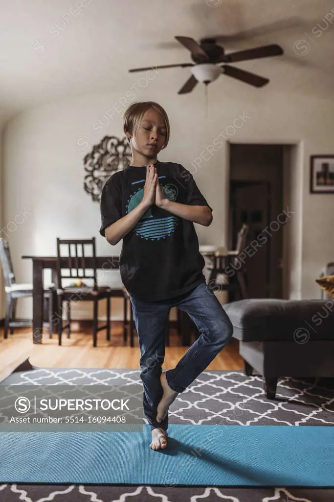 School-age boy doing yoga in living room during isolation