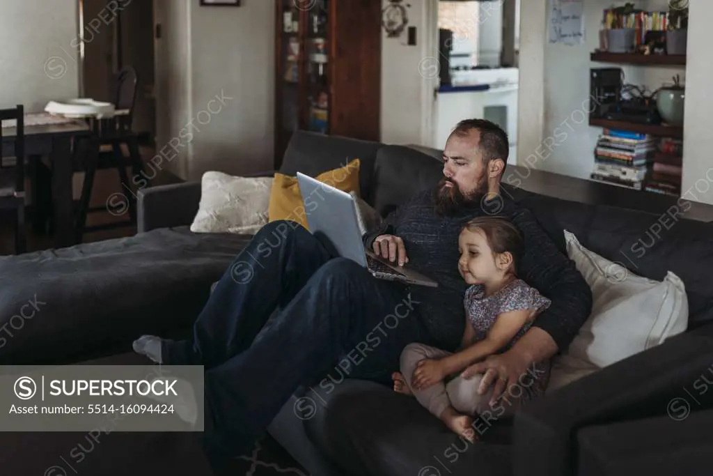 Father working from home with young daughter during isolation