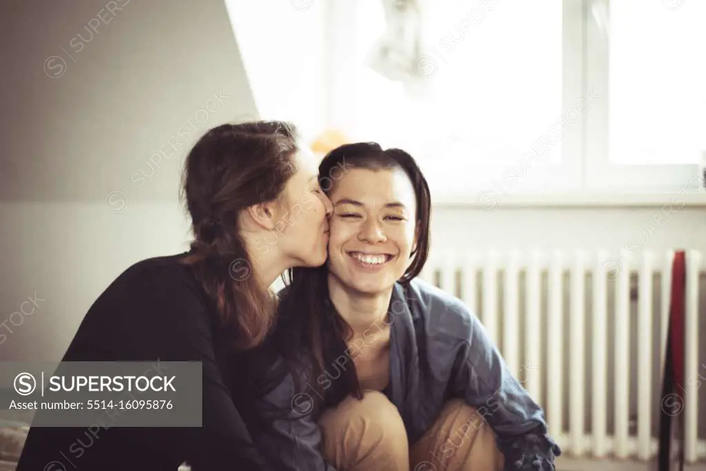 lesbian couple kiss on cheek and stay at home in apartment lock down