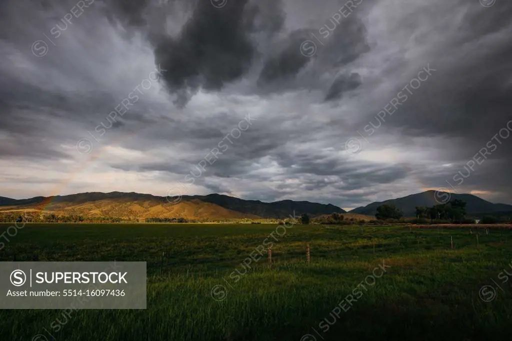 Subtle rainbow in stormy clouds in empty moody field