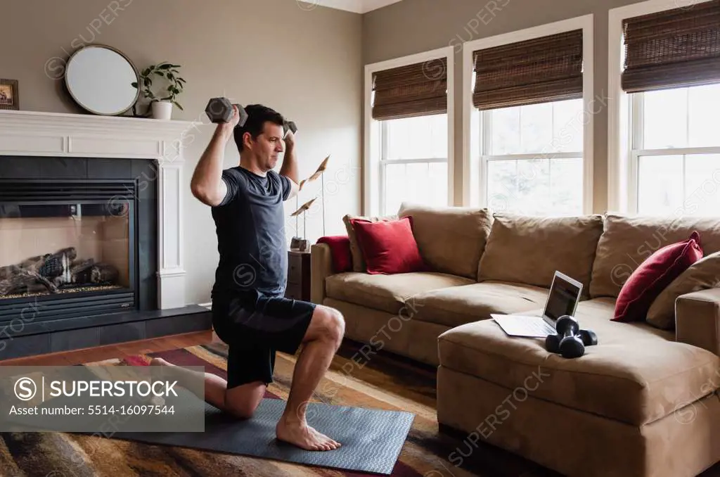 Man working out with weights at home using online exercise program.