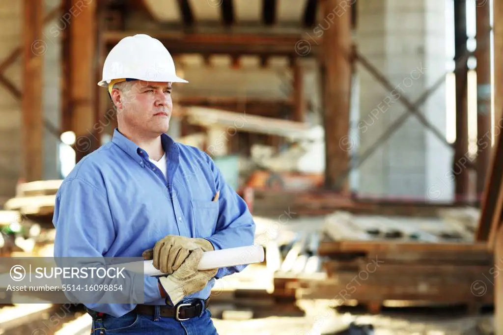 Male construction foreman holding plans looking off camera