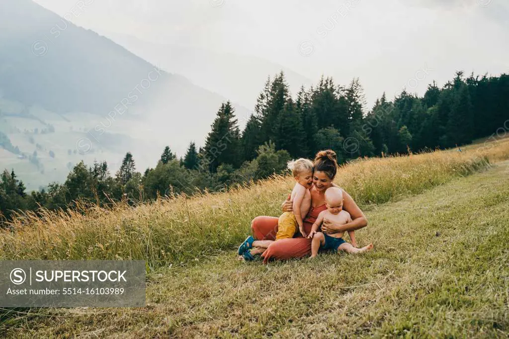 Mom and kids hugging in the mountains sitting on ground