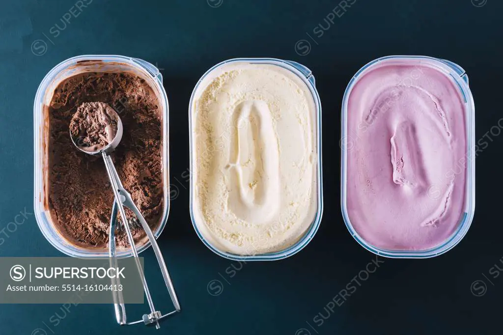 Chocolate, vanilla and strawberry ice cream tubs with scoop