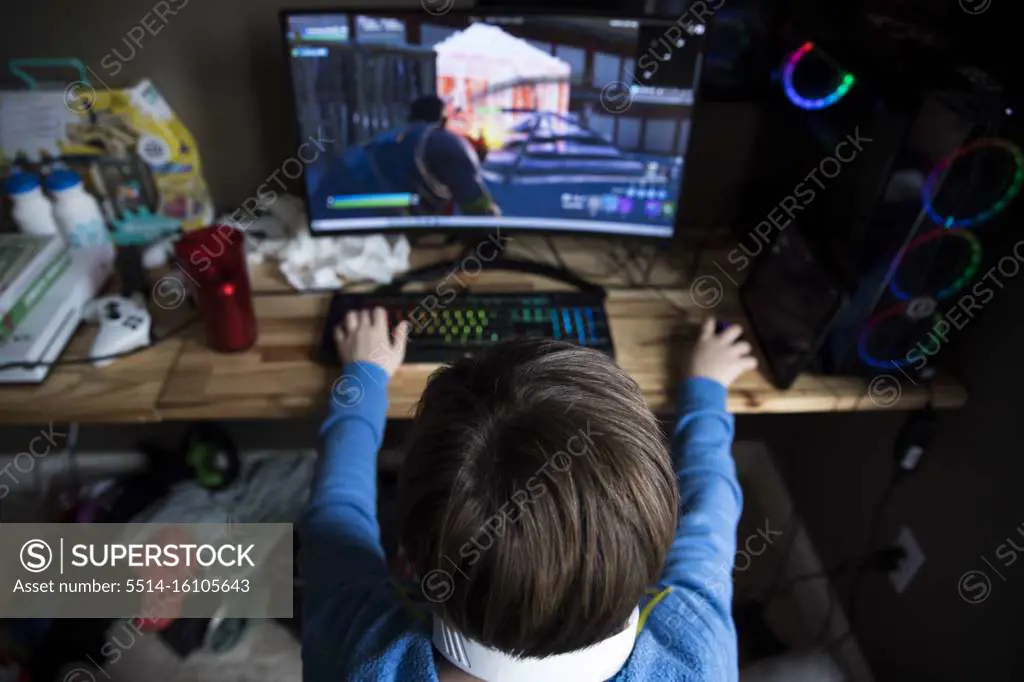 High View of Teen Boy Playing on Gaming Computer at Messy Desk