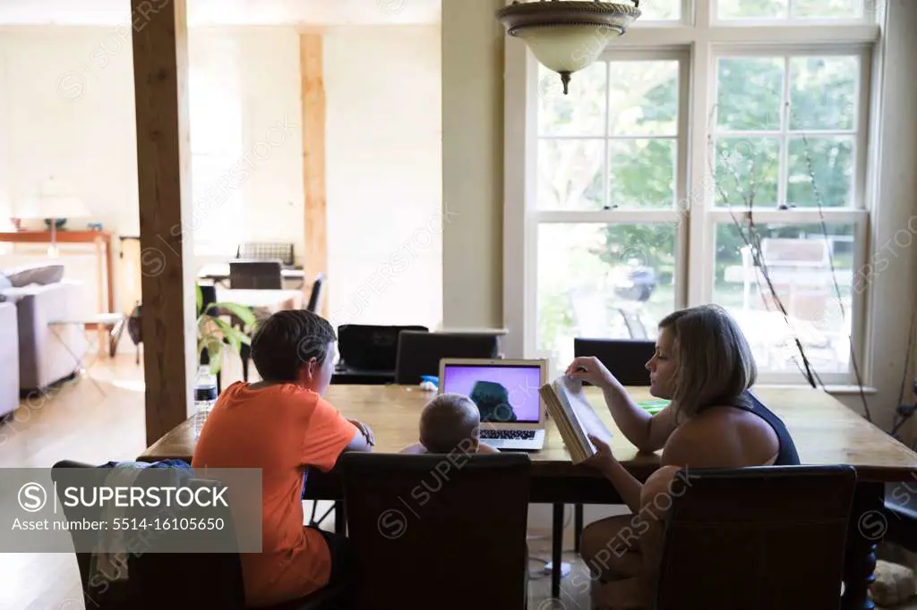 Mom and Toddler Son Watching Laptop Sit With Teenage Cousin at Table