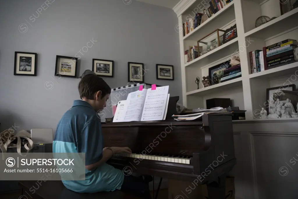 Low Side View of Teen Boy Playing Piano at Home from Marked Pages