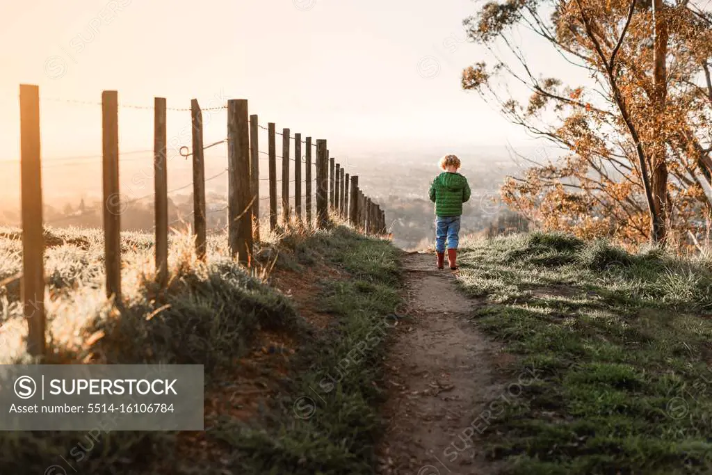 Child walking on path near fence at dusk in New Zealand