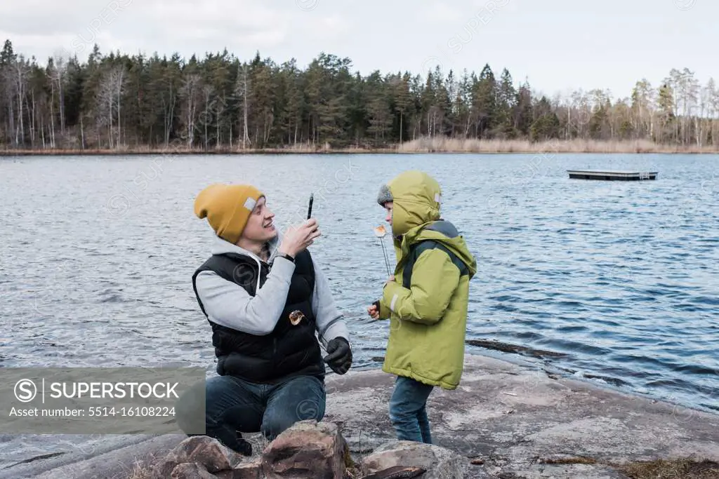 father taking pictures of his son whilst eating marshmallows