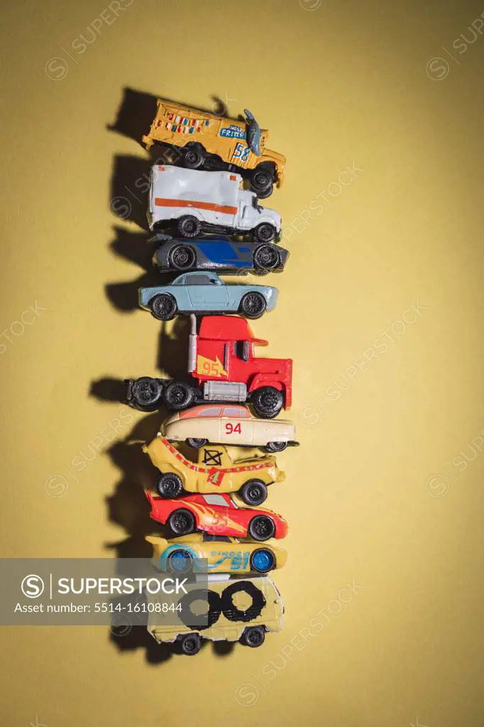 Toy cars stacked on top of each other on yellow background.