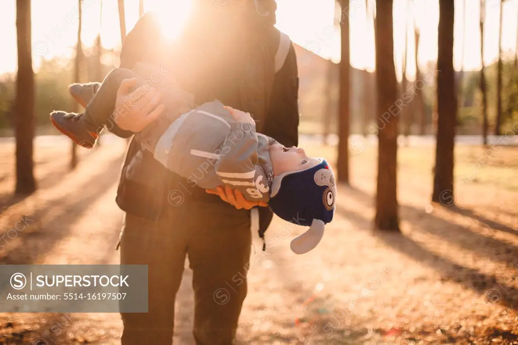 Father playing with son outdoors in park during sunny day in autumn