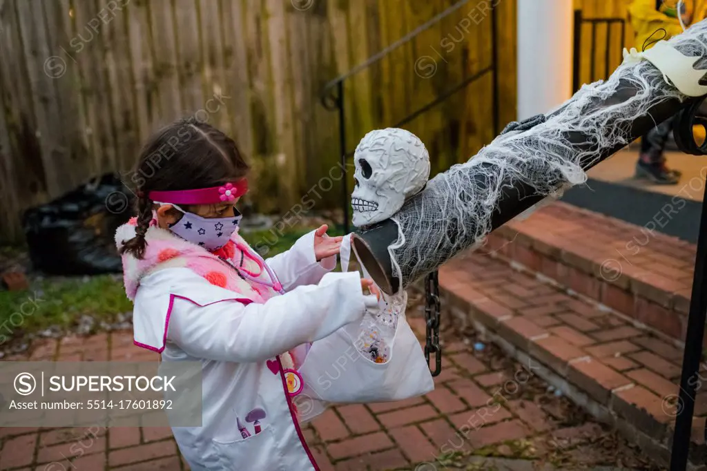 girl in doctor costume socially distant trick or treating candy chute